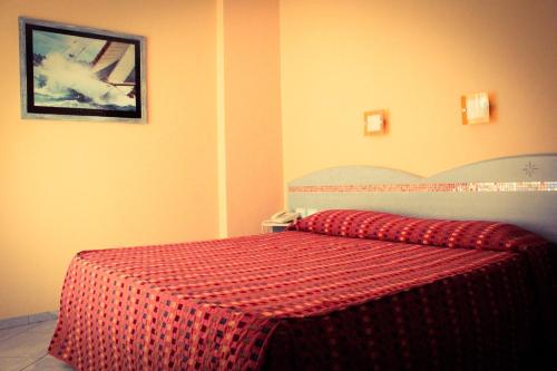 a bedroom with a bed with a red comforter at Hotel Chentu Lunas in Cagliari