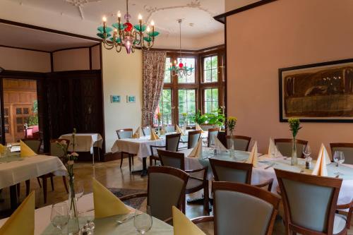 uma sala de jantar com mesas e cadeiras e um lustre em Parkhotel Unter den Linden em Halberstadt