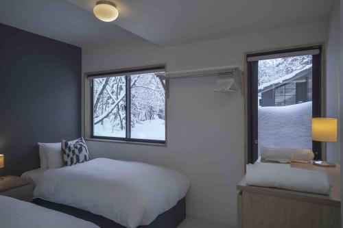 Schlafzimmer mit einem Bett und einem Fenster mit Schnee in der Unterkunft Hakuba Cottage Karamatsu in Hakuba