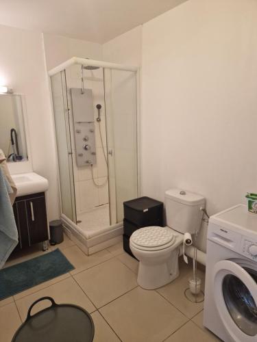 a bathroom with a toilet and a shower and a washing machine at BlueBay Université in Saint-Denis
