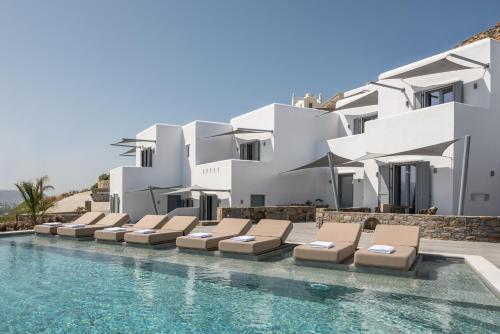 a swimming pool with chaise lounge chairs next to a building at Virtu on the Hill in Stelida