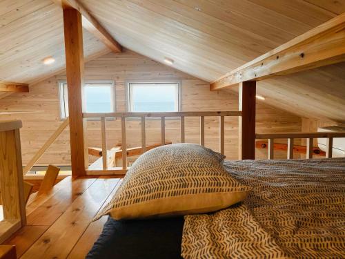 a bedroom with a bed in a wooden cabin at PACIFICO SURF HOUSE - by the Sea in Shishikui