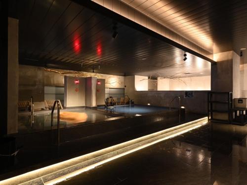a swimming pool in a large room with lights at The Centurion Sauna Rest & Stay Sapporo Male Only in Sapporo