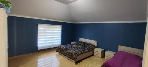 um quarto com uma cama e uma parede azul em Kirayə ev, Qax, Qaşqaçay guesthouse em Qax