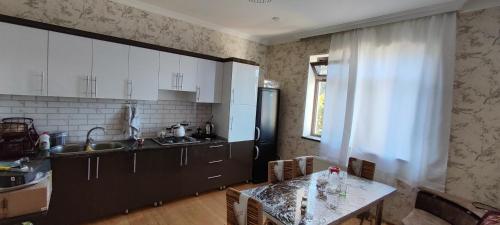 uma cozinha com armários pretos, uma mesa e uma janela em Kirayə ev, Qax, Qaşqaçay guesthouse em Qax