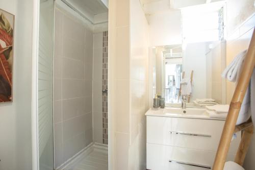 La salle de bains blanche est pourvue d'une douche et d'un lavabo. dans l'établissement 16 - LE VACOA - CHAMBRE 16 ETG D, à Saint-Paul