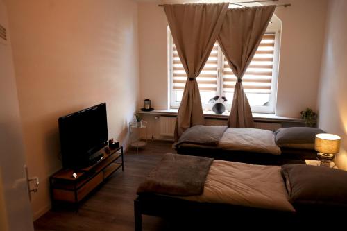 een slaapkamer met 2 bedden, een tv en een raam bij Apartment Kompakt Gottschalk 2.0 in Kassel