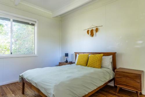 ein Schlafzimmer mit einem Bett mit gelben Kissen und einem Fenster in der Unterkunft Yarroma in Berrara