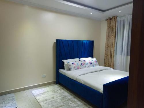 uma cama com uma cabeceira azul num quarto em Atalia Athi River em Nairobi