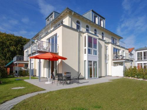 un grande edificio bianco con tavolo e ombrellone di Haus Möwe - Apt. 02 a Ostseebad Sellin