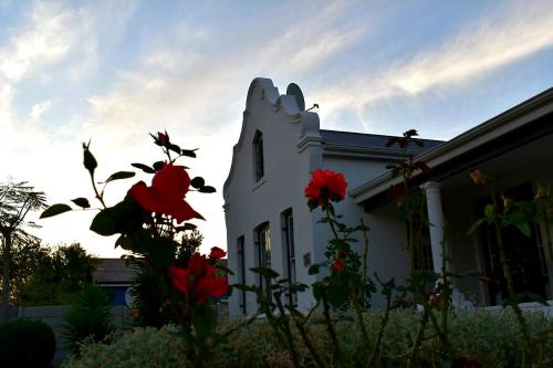 Una casa blanca con flores rojas delante de ella. en The Elizabeth Riviersonderend, en Riviersonderend