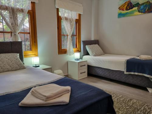 a bedroom with two beds and two windows at Kalkan Centre Bijou Home - Walk to town and beach in Kalkan