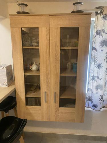 d'une armoire en bois avec des portes en verre et de la vaisselle. dans l'établissement Studio Bandrélé, à Bandrélé