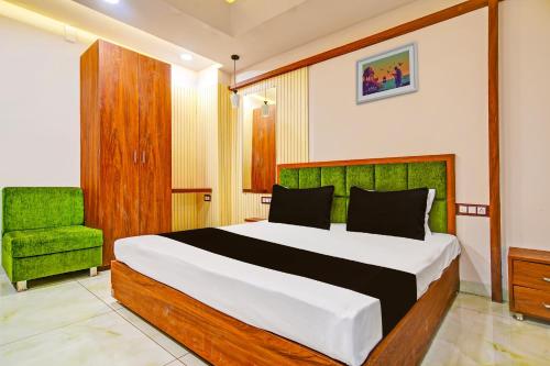 a bedroom with a bed and a green chair at OYO Hotel Shree in Dewās