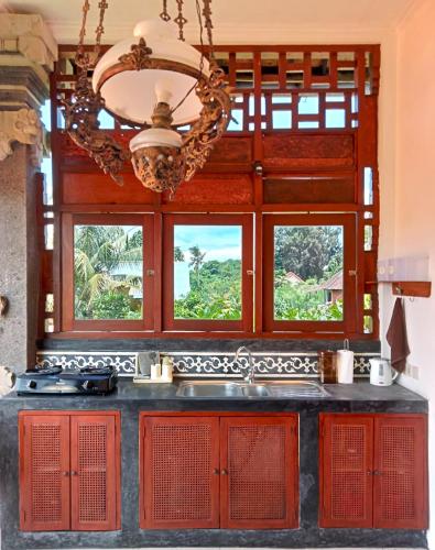 a kitchen with red cabinets and windows and a sink at Lily Lane Villas in Ubud