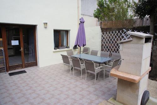 une terrasse avec une table, des chaises et un parasol dans l'établissement Maison de charme au Mont Valérien avec jardin privatif, à Nanterre