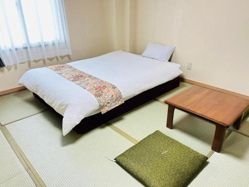 a bedroom with a bed and a wooden table at グリーンホテル会津 in Aizuwakamatsu