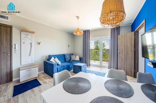 ein Wohnzimmer mit einem Esstisch und einem blauen Sofa in der Unterkunft Pod Brzozami Apartamenty 5 Mórz in Ustronie Morskie