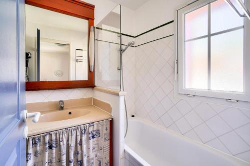 La salle de bains est pourvue d'un lavabo, d'une baignoire et d'une fenêtre. dans l'établissement Les Maisons de Lacanau les Pins - maeva Home - Maison 3 pièces 6 personnes - Sélection MAE-2031, à Lacanau