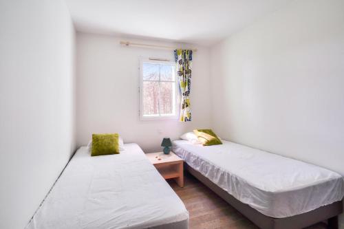deux lits dans une petite pièce avec une fenêtre dans l'établissement Les Maisons de Lacanau les Pins - maeva Home - Maison 3 pièces 8 personnes - Prestige MAE-2061, à Lacanau