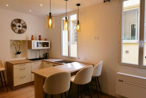 - une cuisine avec une table en bois et des chaises blanches dans l'établissement Cocooning Atmosphère old Nice, à Nice