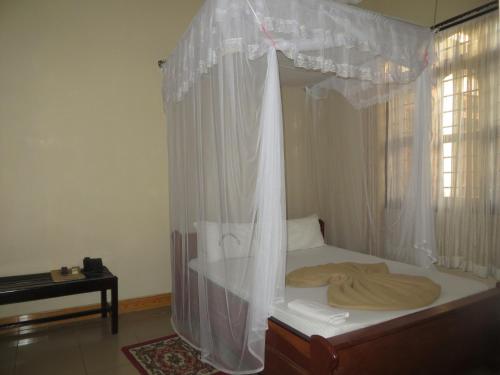 1 dormitorio con cama con dosel y ventana en MIKUMI RESORT HOTEL en Mikumi