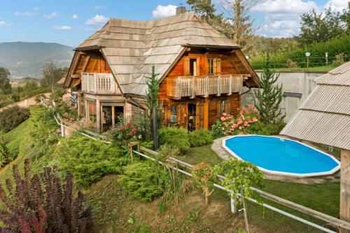 a log house with a swimming pool in front of it at Chalet Podgorje With Pool in Slovenj Gradec
