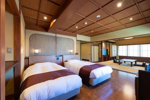 a bedroom with two beds and a table in it at Hotel Sekitei in Fuefuki