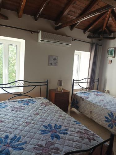 two beds in a room with two windows at Villa Fraoulitsa in Skoutarion