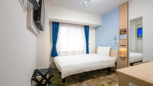 a small room with a bed and a window at Toyoko Inn Higashi-osaka in Higashi-osaka