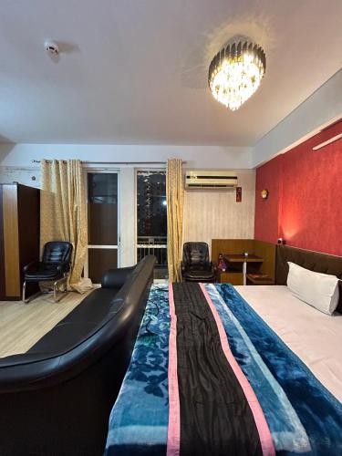 Habitación de hotel con cama grande y lámpara de araña. en Luxsugero Studios Lucknow, en Lucknow