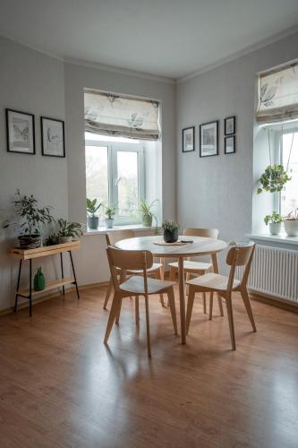 uma sala de jantar com mesa, cadeiras e janelas em Nice&cozy flat No7 em Riga