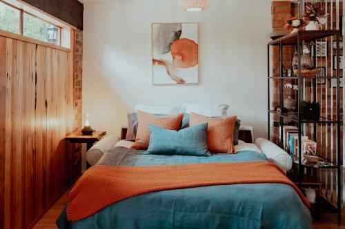 a bedroom with a bed with orange and blue pillows at Outdoor Spa & Sauna with amazing views at Jaclyn Studio in Launceston