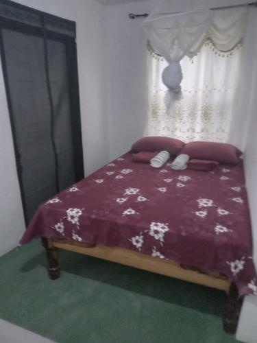 a bedroom with a bed with a purple comforter and a window at Port Antonio Brian's Beach House in Port Antonio