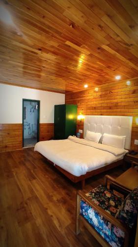 a large bed in a room with wooden ceilings at Highland Heritage cottages in Manāli