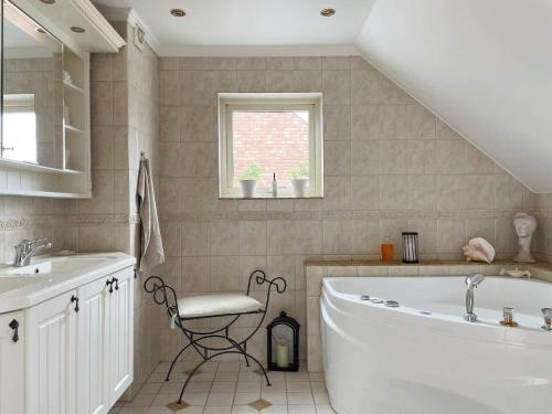 a bathroom with a tub and a sink and a chair at Holiday home SPÅNGA in Stockholm