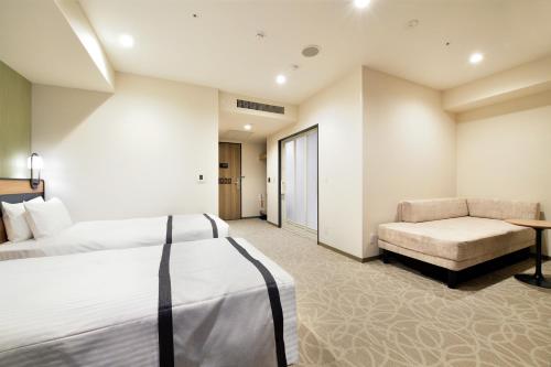a hotel room with two beds and a couch at Hotel Elcient Osaka Umeda in Osaka