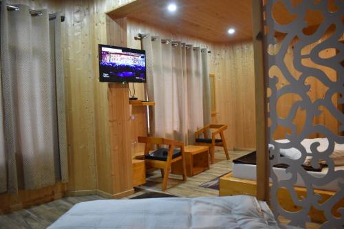 a bedroom with a bed and a flat screen tv at Hotel Badrinath in Badrinath