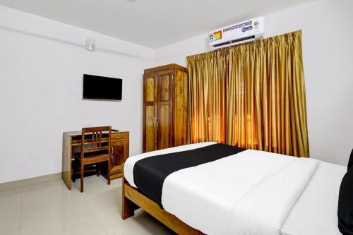 a bedroom with a bed and a cabinet and a television at OYO Timber Near Lulu Mall in Trivandrum
