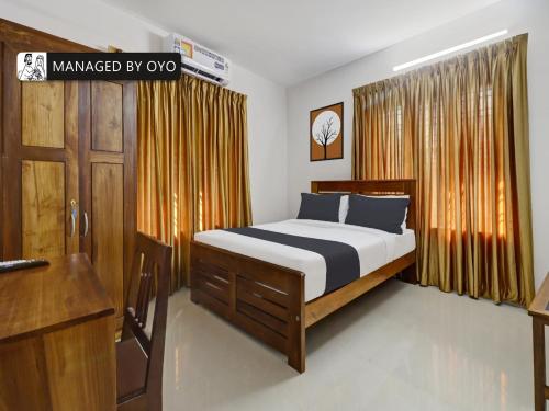 a bedroom with a bed and a dresser in it at OYO Timber Near Lulu Mall in Trivandrum