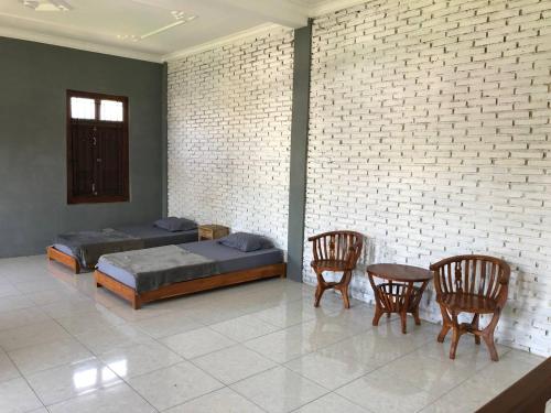 a bedroom with a bed and two chairs and a brick wall at Jasmine Homestay Syariah in Jepara