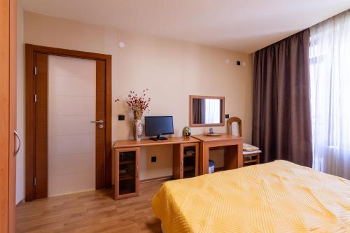 a bedroom with a bed and a desk with a television at Golden Sands 1BD Summer Retreat by Flat Mаnаger in Golden Sands