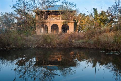 a building sitting next to a body of water at Jim's Jungle Retreat in Rāmnagar