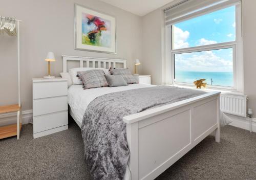 a white bedroom with a large bed and a window at Sealight in Pwllheli