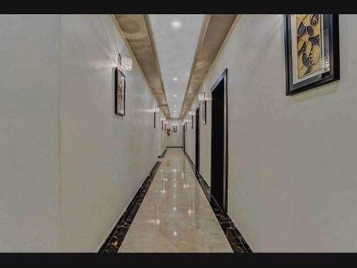 un pasillo con un largo pasillo con paredes blancas en Hotel Raas Near M2k Cinemas Rohini, en Nueva Delhi