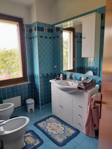 a bathroom with a sink and a toilet and a mirror at Bed & Breakfast Agriturismo San Macario in Pula