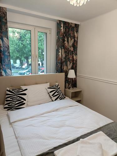 1 cama blanca en un dormitorio con ventana en Tabago Studio 19, en Kędzierzyn-Koźle