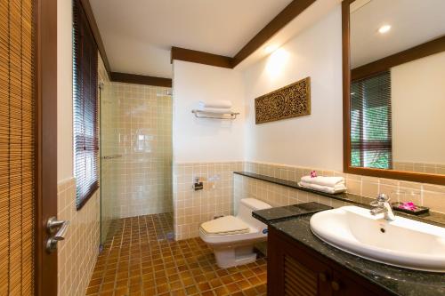 W łazience znajduje się umywalka, toaleta i lustro. w obiekcie Katamanda villa Sooksan w mieście Kata Beach