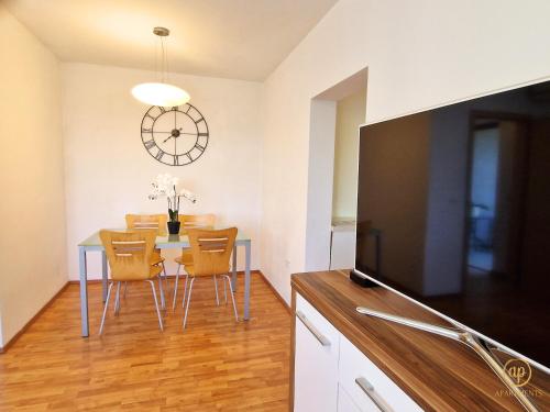 a dining room with a table and chairs and a clock at Apartment Saria Strunjan in Strunjan