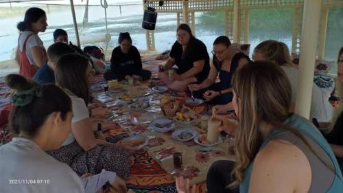 un grupo de personas sentadas alrededor de una mesa comiendo comida en Hamo Fathy Nubian House, en Asuán